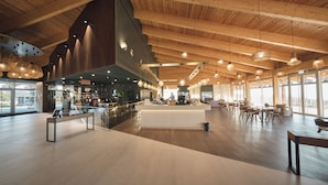 Eine geräumige Lobby mit hoher Decke, Holzbalken und moderner Pendelleuchten.