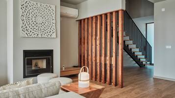 Un salon moderne doté d’une cheminée, d’une cloison en bois et d’un escalier menant à un autre niveau.