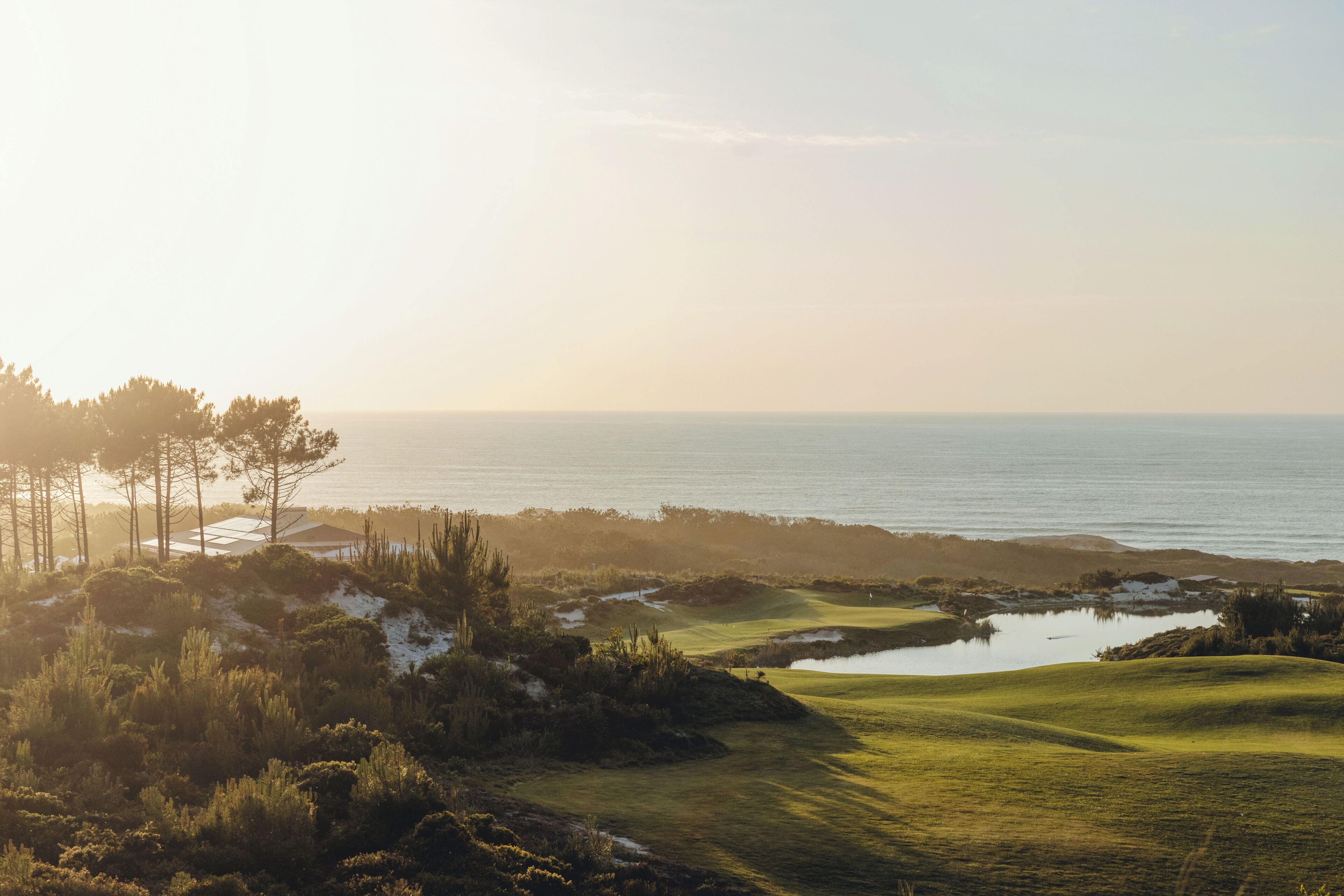 Un parcours de golf avec des obstacles d’eau, des arbres et une vue sur l’océan.