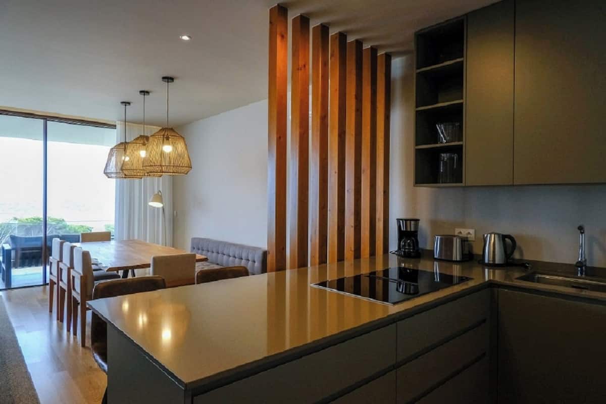 A modern kitchen with a central island, wooden accents, and built-in appliances.