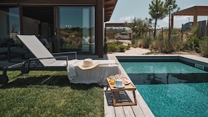 Ein Poolbereich mit Liegestuhl, Sonnenhut und einem Tablett mit Frühstücksleckereien.