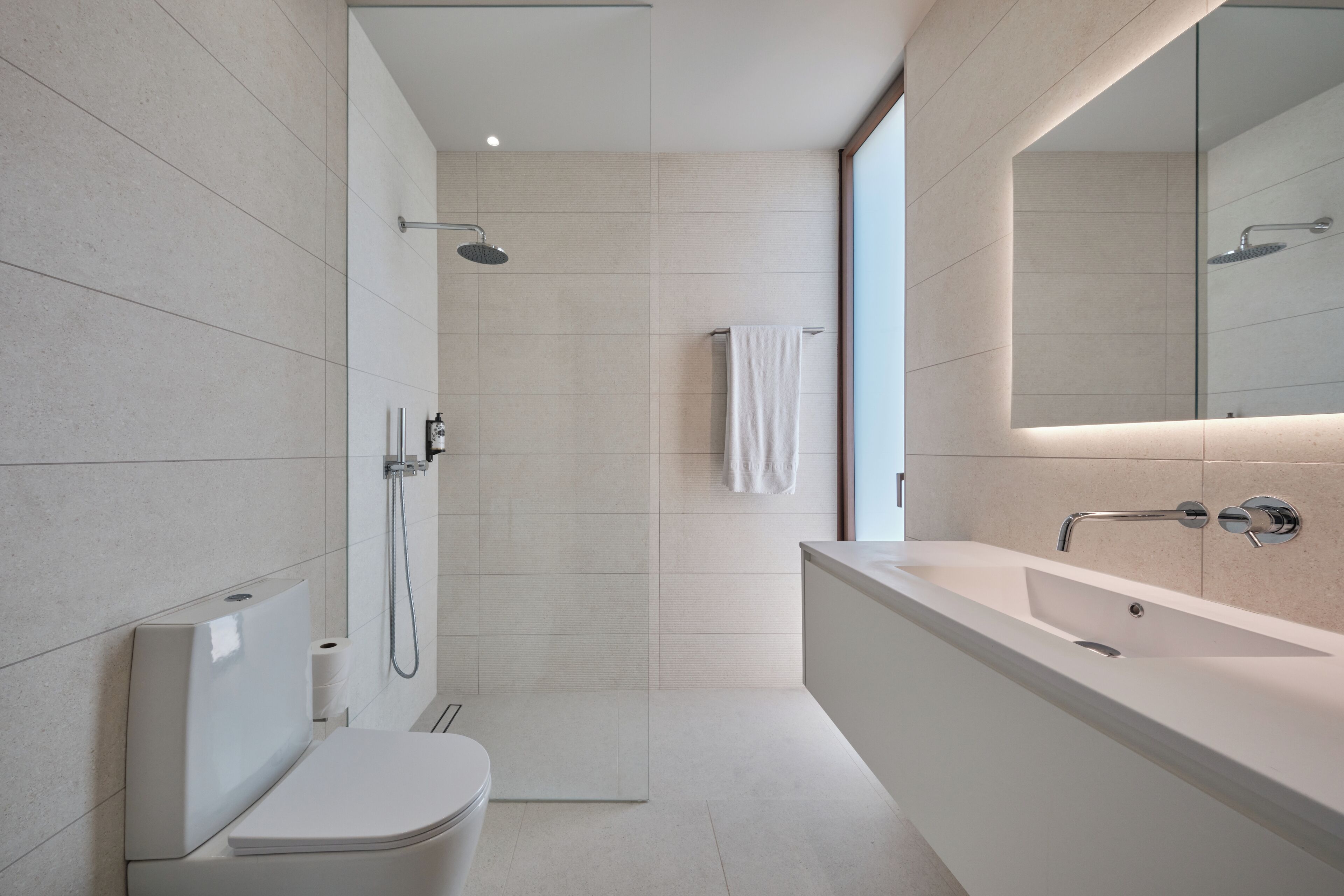 A modern bathroom with a shower, toilet, and a large bathtub.