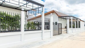 A modern house with a large glass window, a metal gate, and a covered porch. - Tonsoi Hathairat (Bangkok)