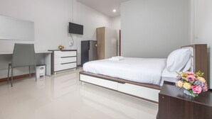 A modern hotel room with a bed, a desk, a chair, a TV, a wardrobe, and a small table with a flower arrangement. - Tonsoi Hathairat (Bangkok)