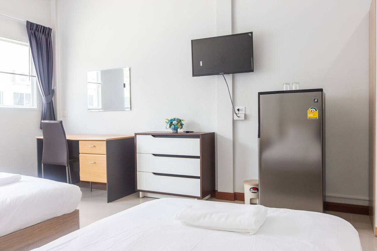 Ein Hotelzimmer mit Bett, Schreibtisch, Stuhl, Fernseher und Kühlschrank.