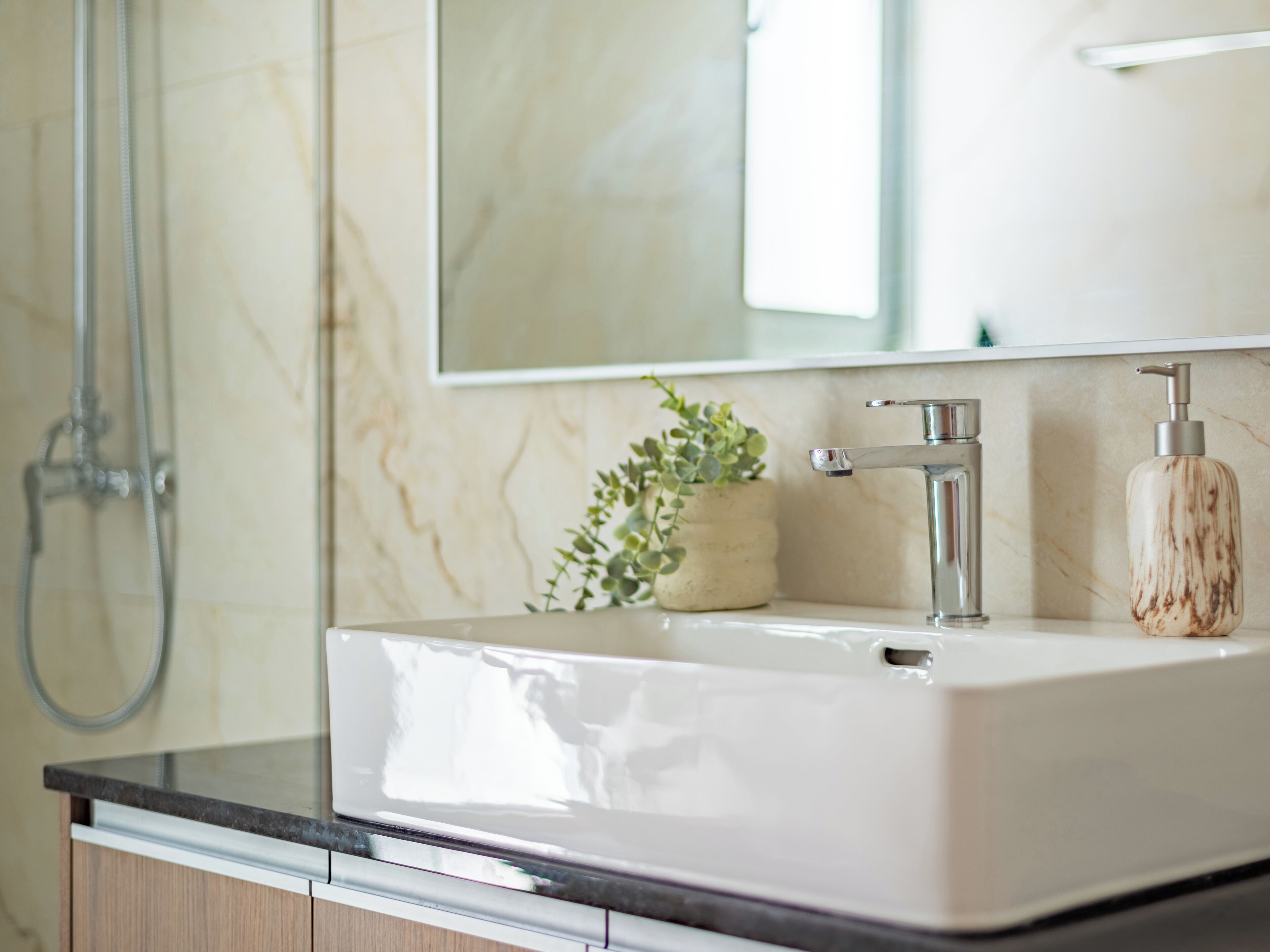 Une salle de bain avec un lavabo blanc, un miroir et une douche.