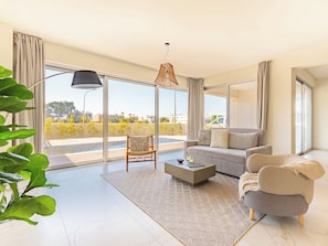 Relax in this stylish living room with a sofa, armchair, and balcony access.