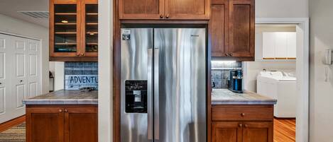 A kitchen with wooden cabinets, a stainless steel refrigerator, and a coffee maker.
