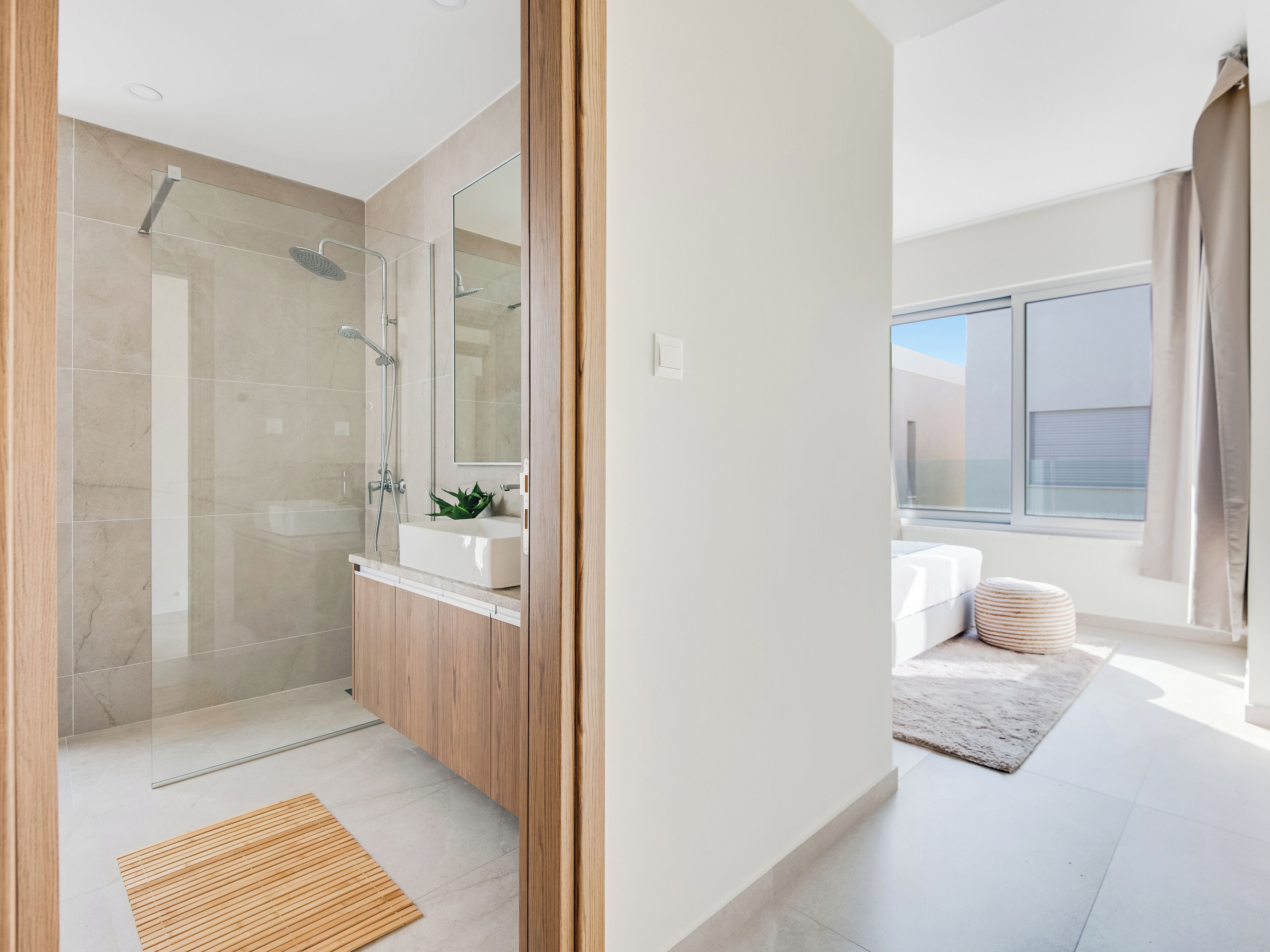 A modern bathroom with a glass-enclosed shower, a wooden vanity, and a large mirror.