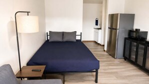A modern, compact room with a bed, a sofa, a small table, a lamp, a refrigerator, and a microwave. - Stand Rock Studios in Wisconsin Dells! (Wisconsin Dells)