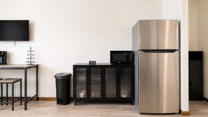 Une petite cuisine équipée d’un réfrigérateur en acier inoxydable, d’un four à micro-ondes, d’une machine à café et d’une poubelle.