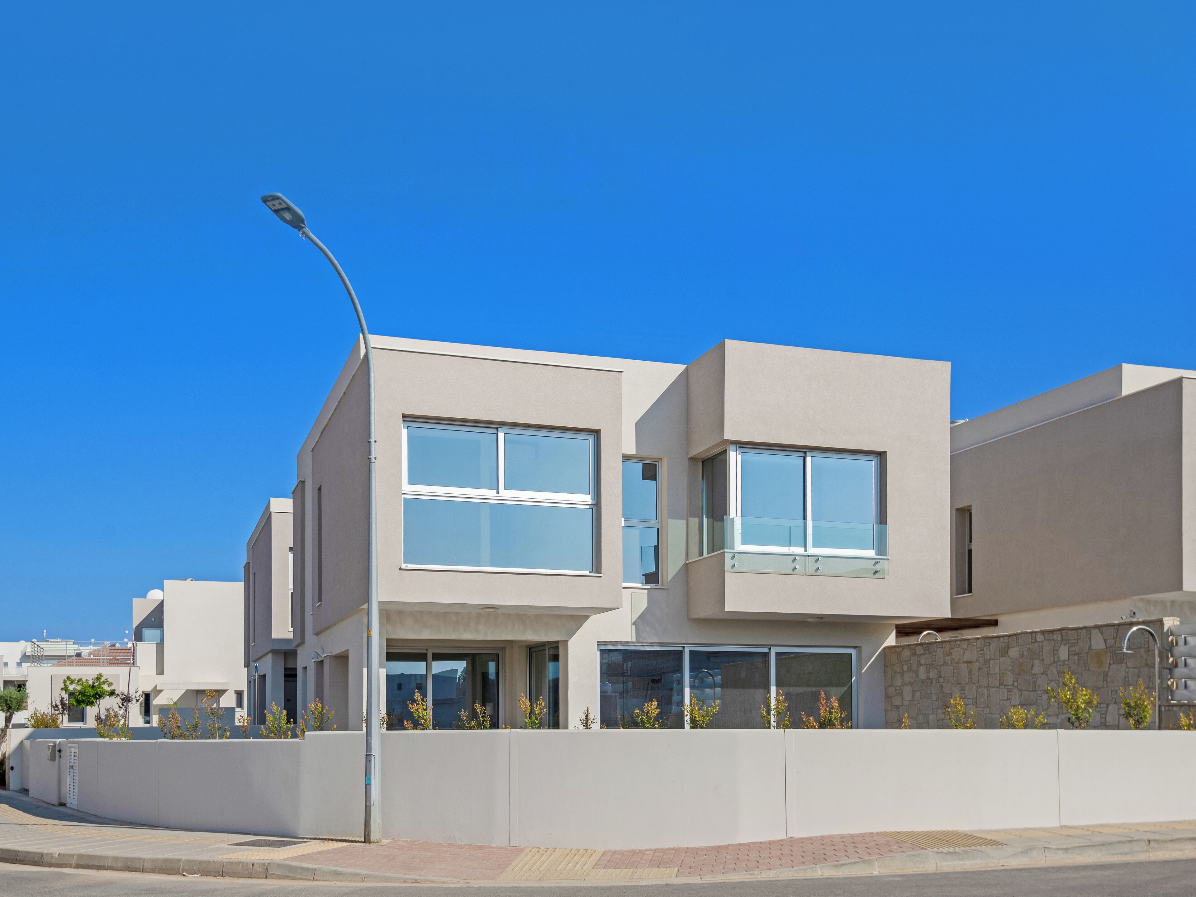 A modern two-story residential building with large windows and a stone wall.
