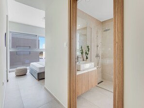A modern bathroom with a glass shower enclosure, a wooden vanity, and a large mirror.