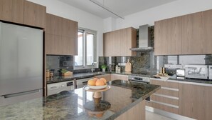 Een moderne keuken met houten kastjes, een Bosch koelkast, een granieten aanrechtblad en een centraal eiland met een schaal fruit.