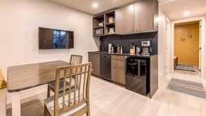 Una cucina compatta con angolo ristoro, elettrodomestici integrati e TV a schermo piatto.