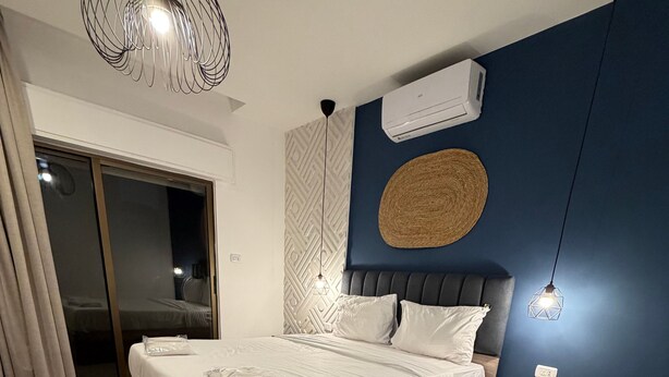 Ein Schlafzimmer mit Bett, Nachttisch, Wandklimaanlage und Deckenventilator.