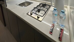 A modern kitchen with a built-in microwave, a gas stove, a sink, and a kettle. - JRE Modern Apartment In Abdoun-amman (Amman)
