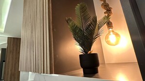 A modern interior with a potted plant, a hanging light fixture, and a wooden slat wall. - JRE Modern Apartment In Abdoun-amman (Amman)