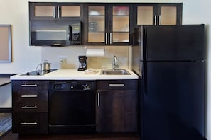 A compact kitchen with dark wooden cabinets, a black refrigerator, a microwave, a dishwasher, and a coffee maker. - Family-friendly Haven! 3 Spacious Units, Pet-friendly Property, Full Kitchen! (Oklahoma City)