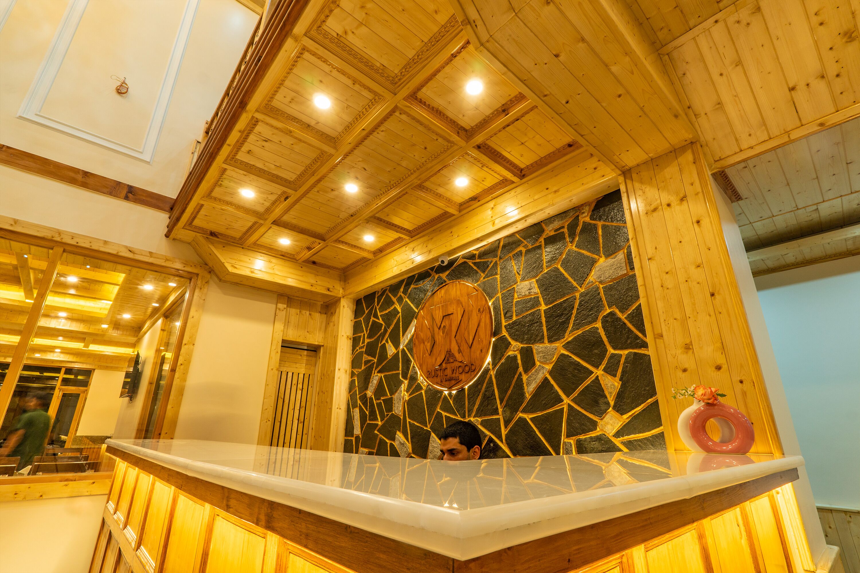 A reception area with a wooden ceiling, a stone mosaic wall, and a reception desk.