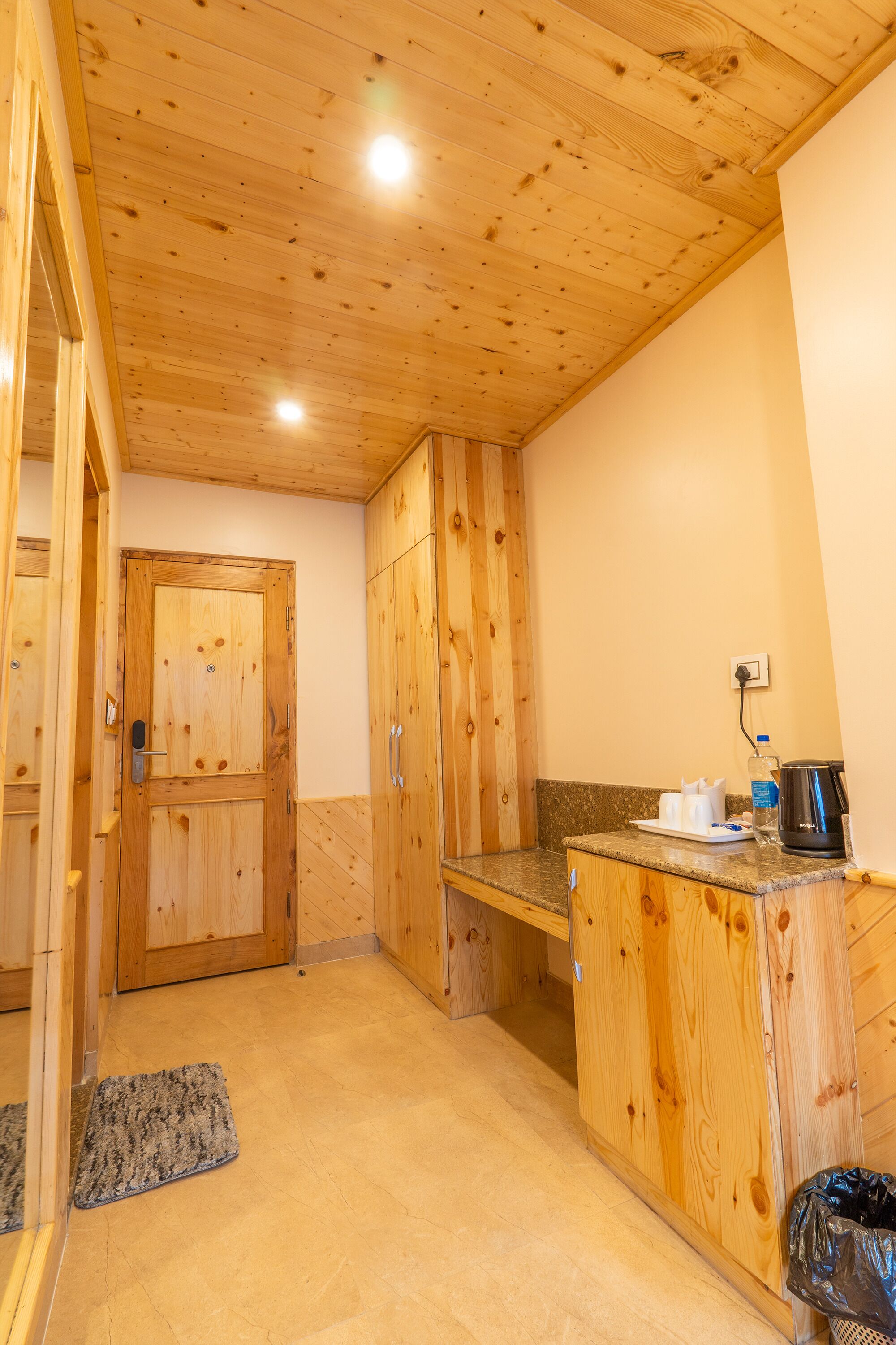Un intérieur en bois avec une porte, un comptoir muni d’une bouilloire et une poubelle.