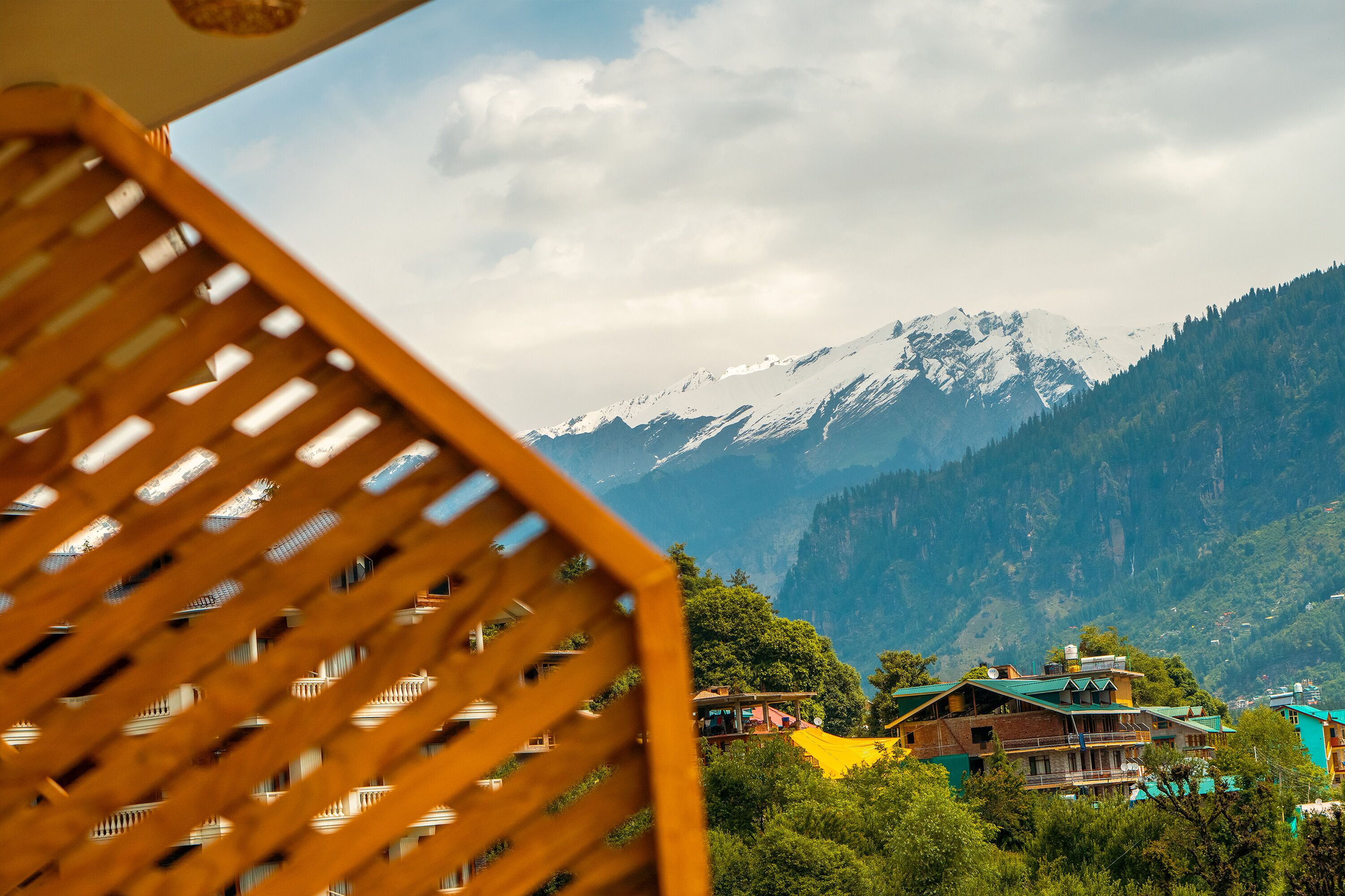 A mountain landscape with snow-capped peaks and a view of a village with traditional houses.