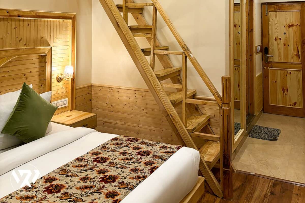 Een slaapkamer met een houten trap, een bed met bloemenbedekking en een nachtkastje met een lamp.