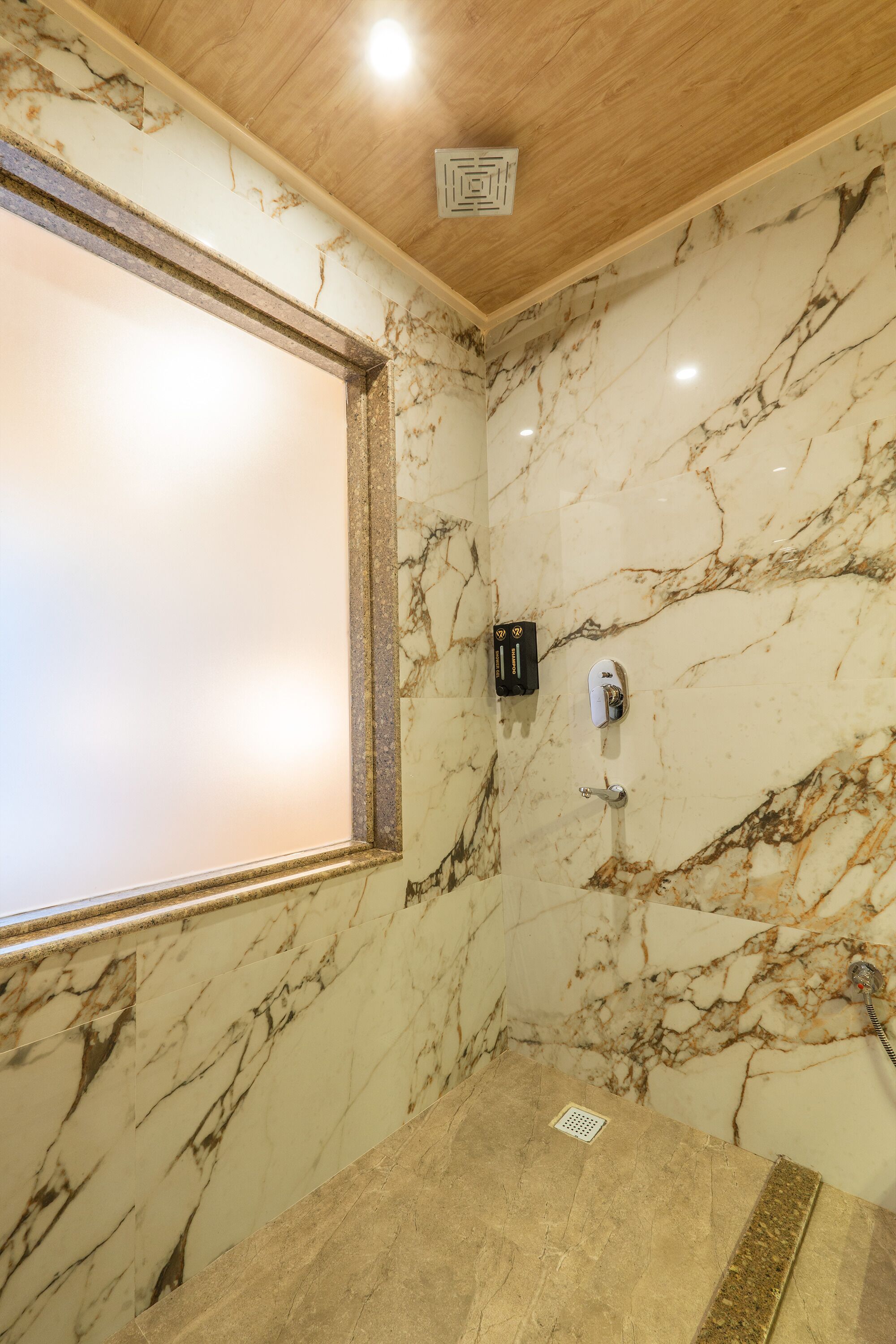Un baño con paredes de mármol, techo de madera y zona de ducha.