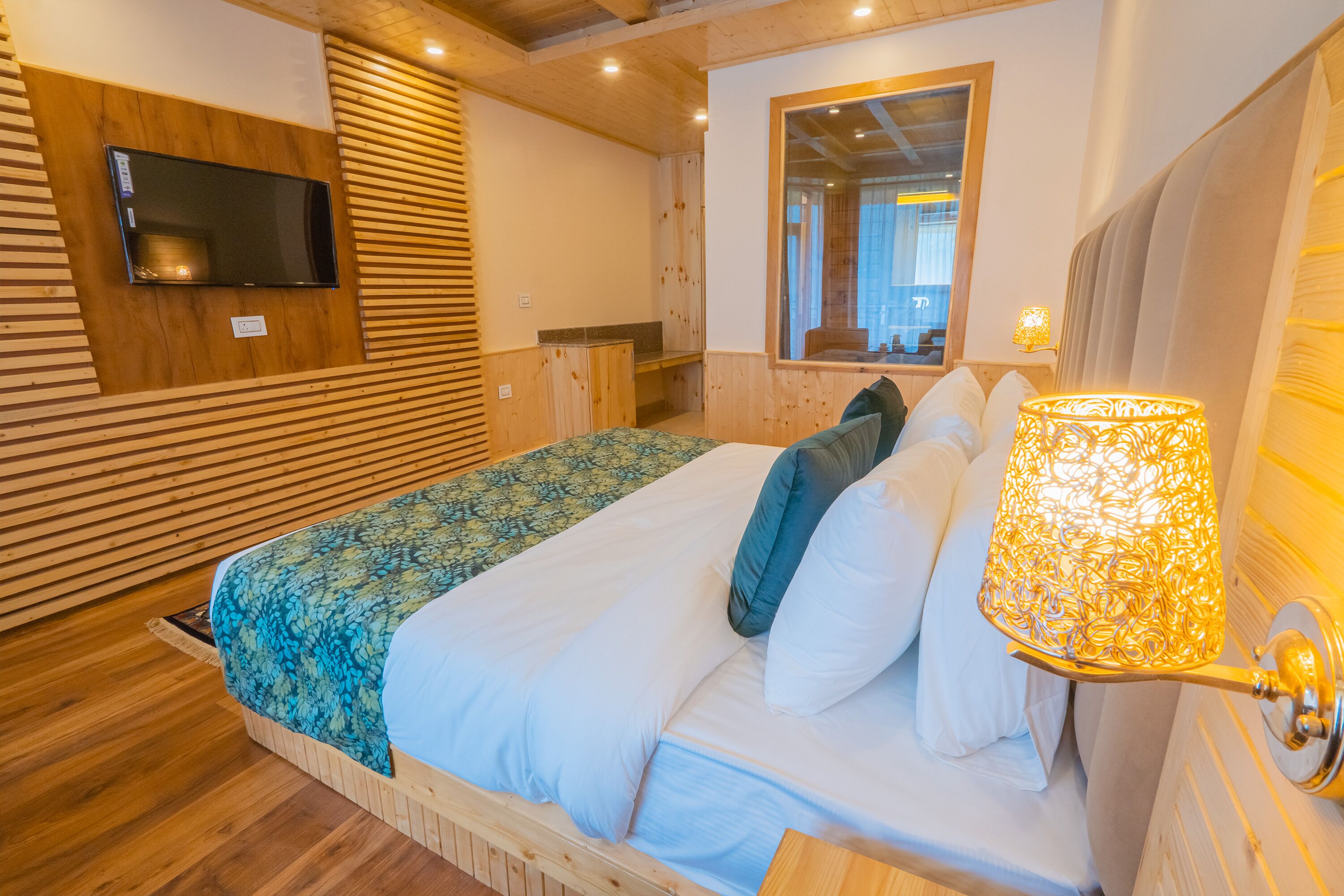 A wooden-paneled room with a bed, a television, and a mirror.