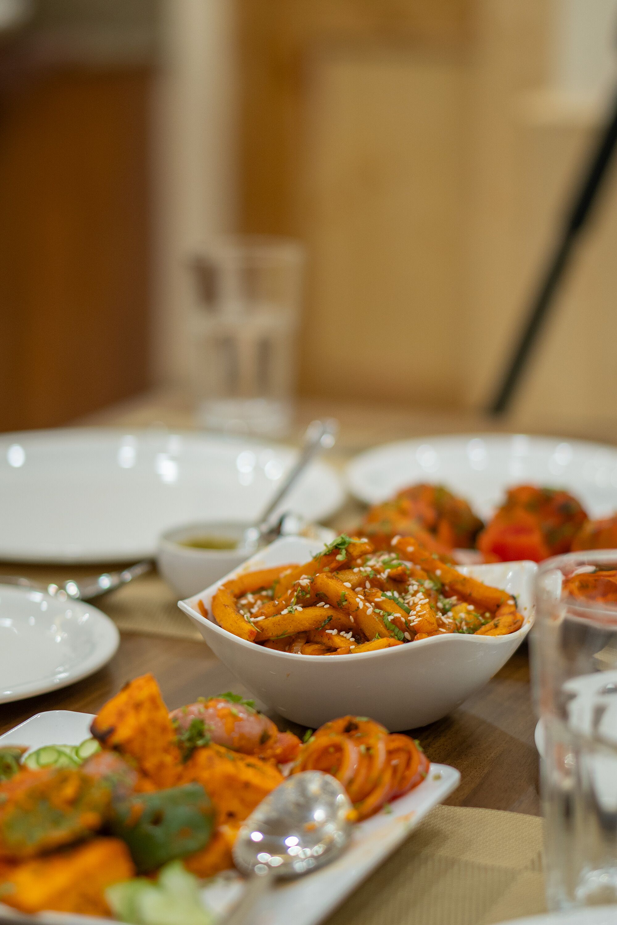 A dining table with various dishes, including a bowl of pasta and a plate of vegetables.