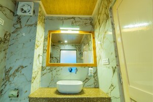 A bathroom with a marble wall, a sink, a mirror, and a ceiling fan.