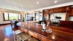 Una cocina con armarios de madera, una isla grande con taburetes de bar, un piano y una estufa.