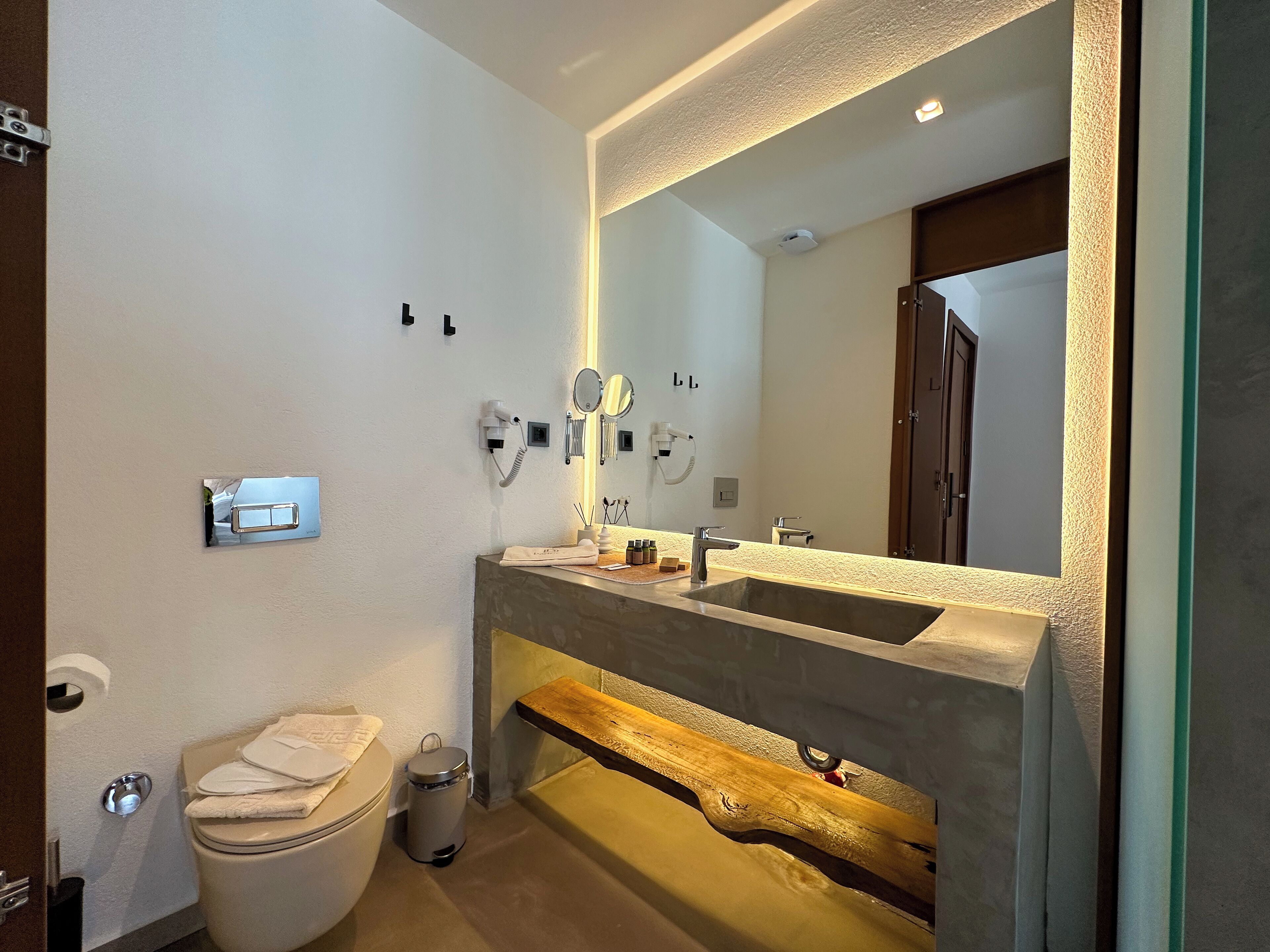 Un baño moderno con un espejo grande, un lavamanos integrado y un inodoro.