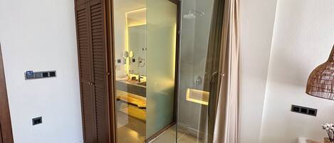 Un baño moderno con ducha de vidrio, tocador con espejo y barra para toallas.