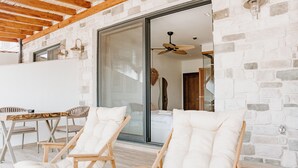 A modern outdoor seating area with wooden furniture and a glass door leading to a room. - Donmez Otel (Urla)