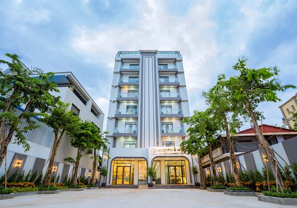 A multi-story hotel with a central entrance, surrounded by trees and a well-maintained garden. - THE SQUARE KAMPOT HOTEL (Kampot)