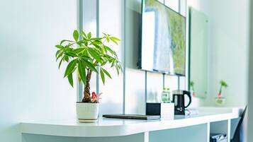 A modern reception desk with a potted plant, a flat-screen TV, and a coffee maker.