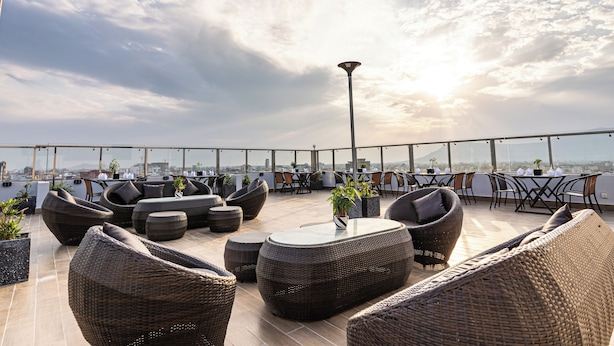 Une terrasse sur le toit, aménagée avec des meubles en osier, des plantes en pot et offrant une vue sur le paysage urbain.
