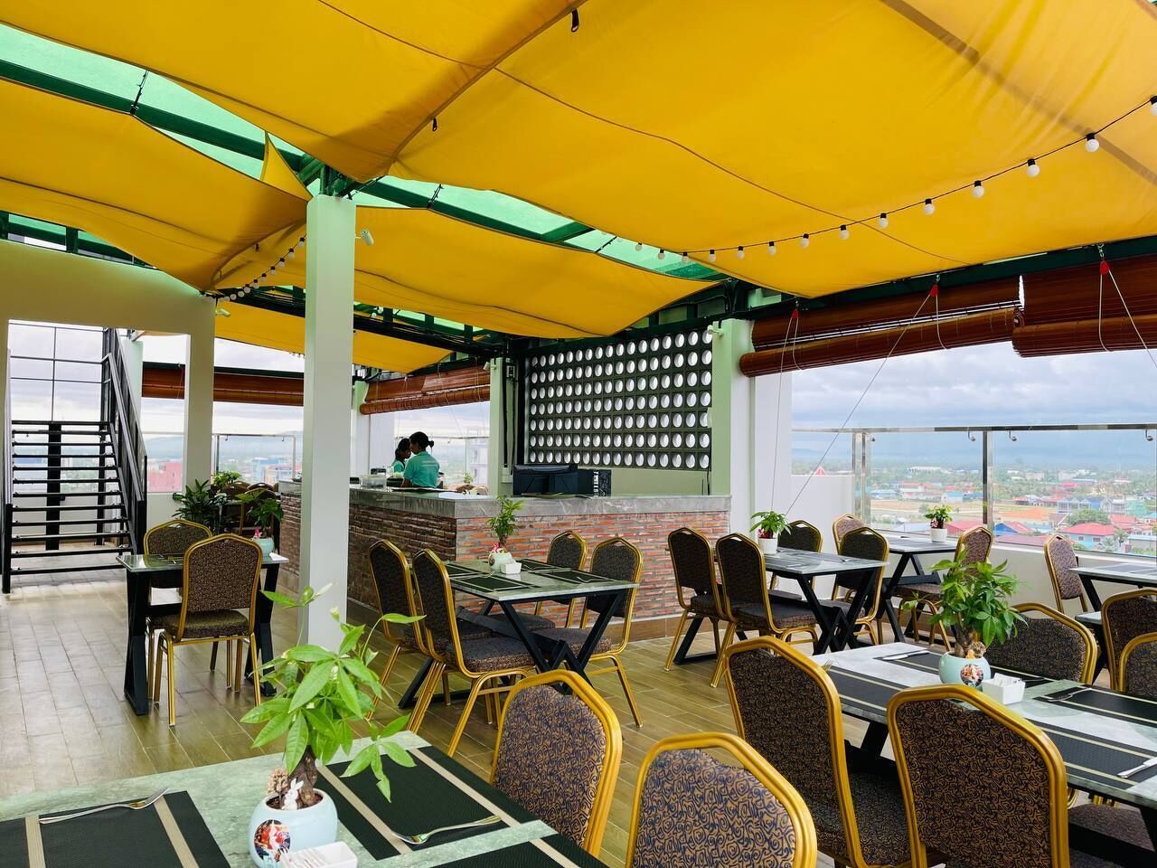 An outdoor restaurant with yellow canopies, tables, and chairs.