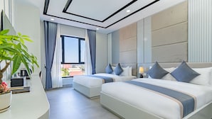 Une chambre d’hôtel moderne avec deux lits, un bureau incurvé et une grande fenêtre avec des rideaux.
