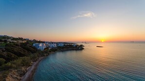 A coastal town with buildings along the shoreline, a clear sky, and a calm sea at sunset. - Nikolas Hotel (Paros)