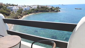 A balcony with a clear view of the sea, a small round table, and white buildings in the background. - Nikolas Hotel (Paros)