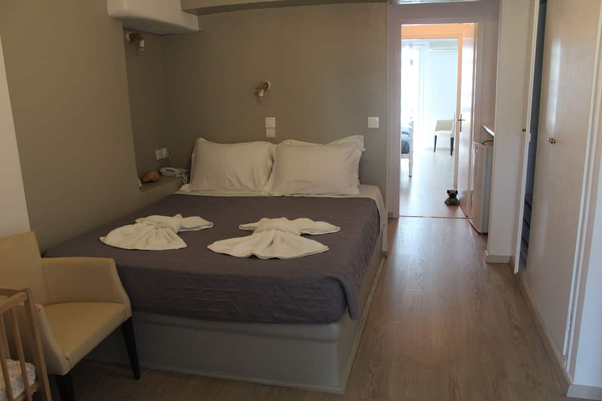 A hotel room with a bed, a chair, and a hallway leading to another room.