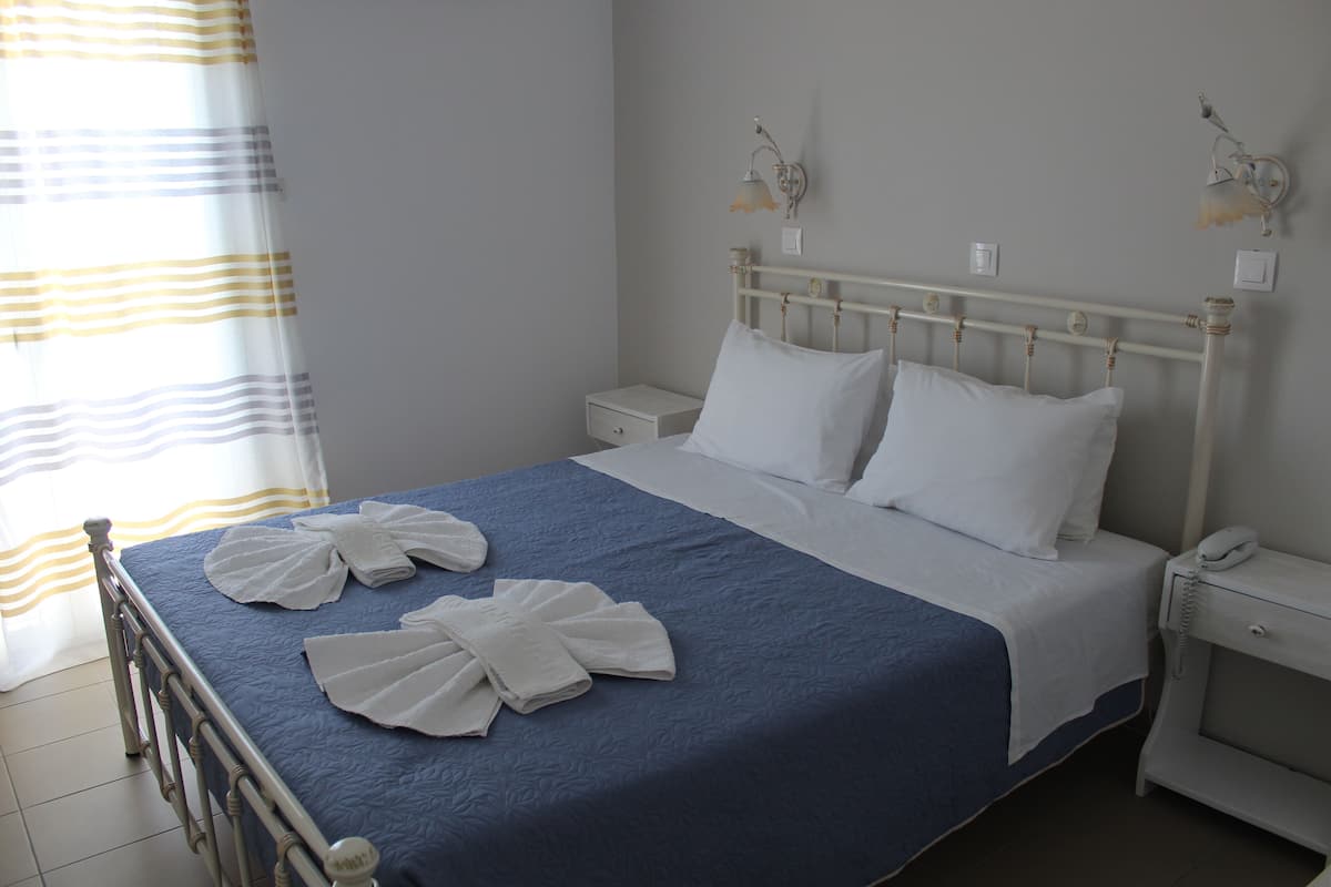 A neatly made bed with white linens, a blue bedspread, and two wall-mounted lamps.