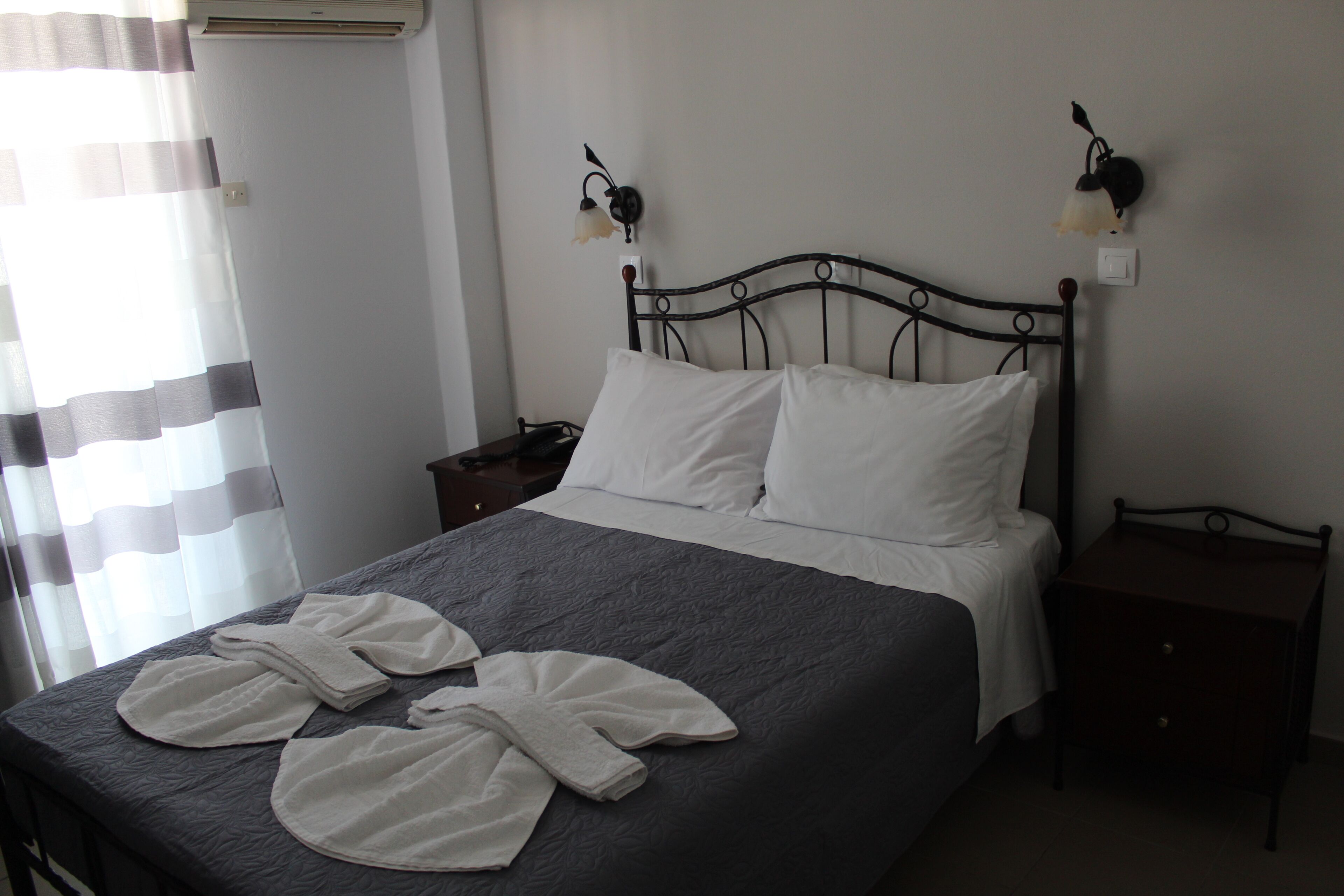 A neatly made bed with white linens and two bedside lamps.