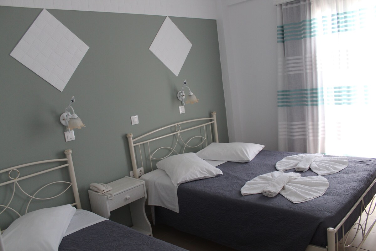 A twin room with two beds, a bedside table with a phone, and a wall-mounted lamp.