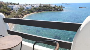 A balcony with a clear view of the sea, a small round table, and white buildings in the background. - Nikolas Hotel (Paros)