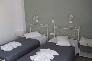 Two single beds with white headboards and nightstands, each with a white lamp and a phone. - Nikolas Hotel (Paros)