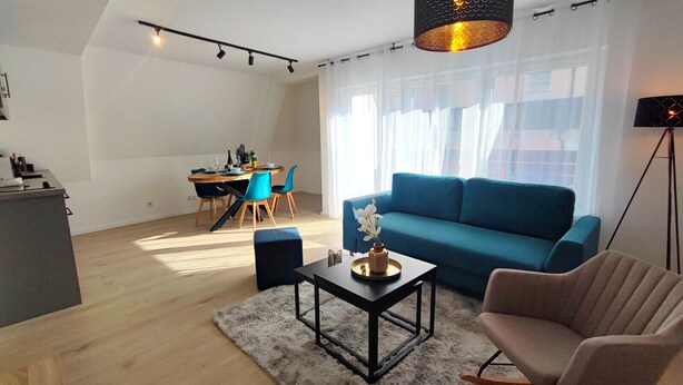 Una sala de estar moderna con un sofá azul, una mesa de centro y un comedor con sillas azules.