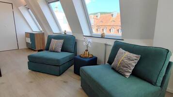 Um loft moderno com dois sofás verde-água, uma mesinha lateral e um radiador.